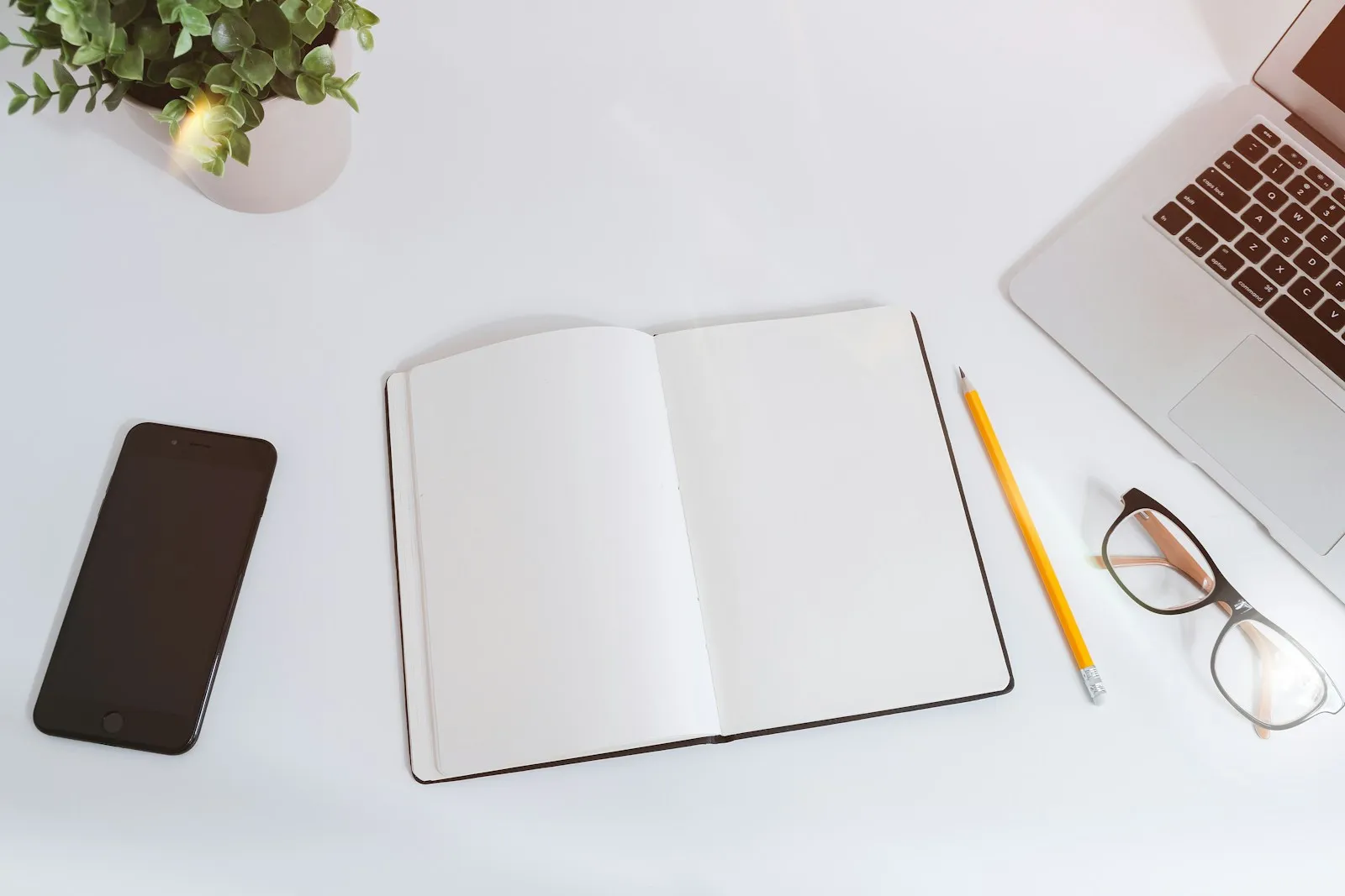 Notebook, pencil, and laptop arranged on a desk for planning